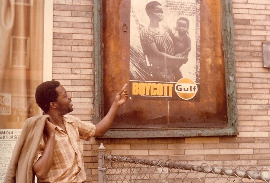 Chris Nteta of the Pan-African Liberation Committee (PALC) outside the Multiservice Center in Roxbury, Massachusetts in 1971 or 1972 with a Boycott Gulf poster produced by the Committee. Gulf Oil was exploiting oil in the Portuguese colony of Angola, providing Portugal with a large amount of revenue that it used in its war efforts against the liberation movements in its colonies (Angola, Mozambique and Guinea-Bissau). PALC sought to get people to boycott Gulf and for Harvard to sell its shares in the company. Nteta, A South Africa exile and then a student at Harvard Divinity School, remained a leader of the solidarity movement in Massachusetts until the end of apartheid.